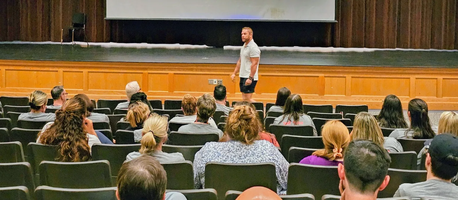 A full auditorium of people seated facing the stage during a CRAVE session.