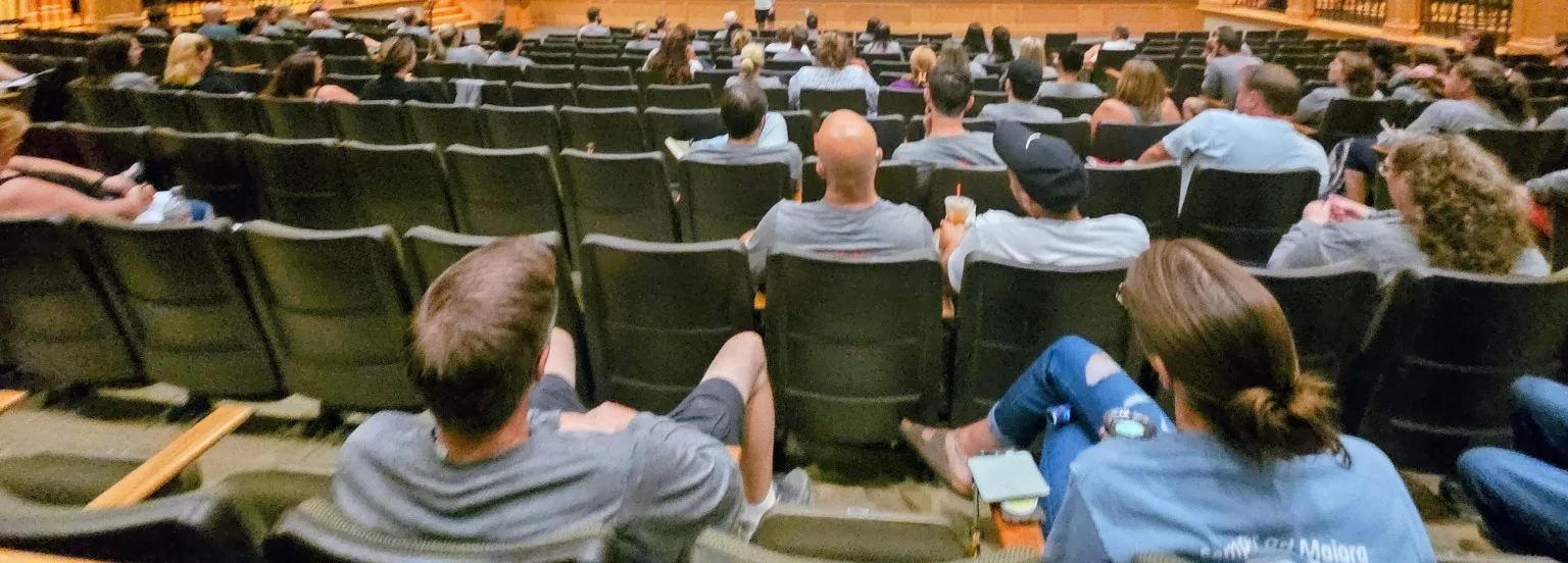 Rows of seated people facing the stage during a CRAVE session.